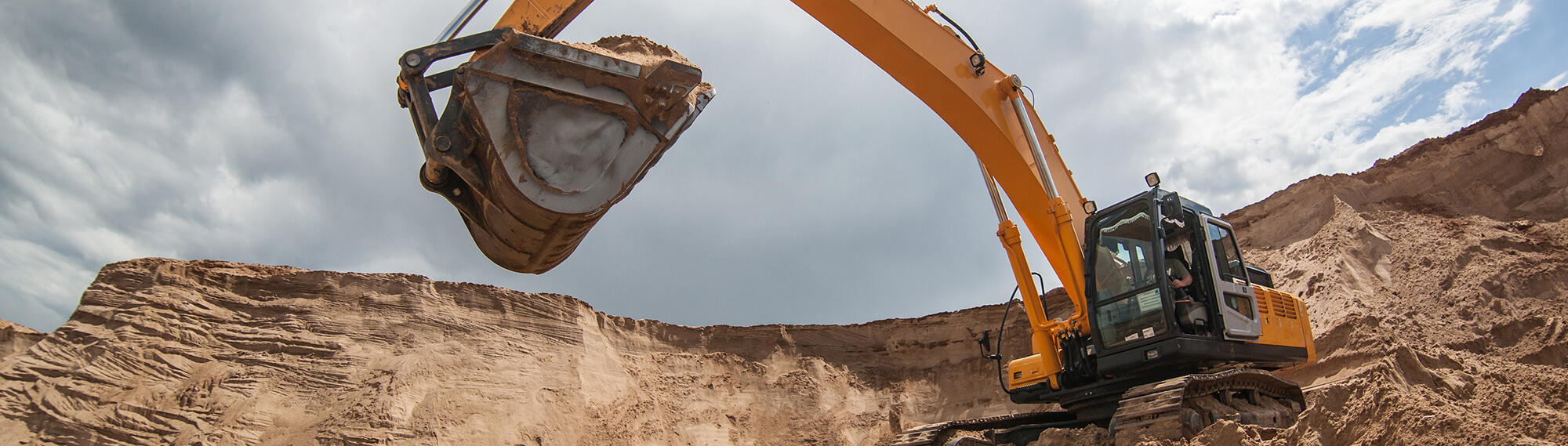 Excavator inside a gravel pit with a huge bucket of aggregate